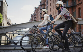 Ein Paar fährt mit E-Bikes über eine Brücke in Hamburg.
