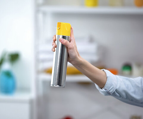 Eine Frauenhand sprüht Lufterfrischer im Zimmer.