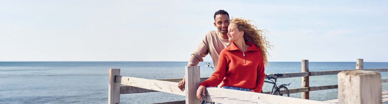 Ein Mann und eine Frau stehen auf einem Steg und gucken in die Ferne.