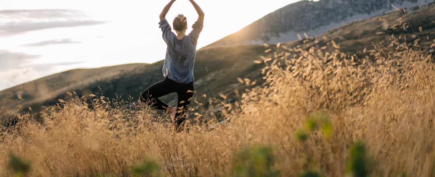 Junge Frau pformt Yoga in den Bergen im Morgenlicht