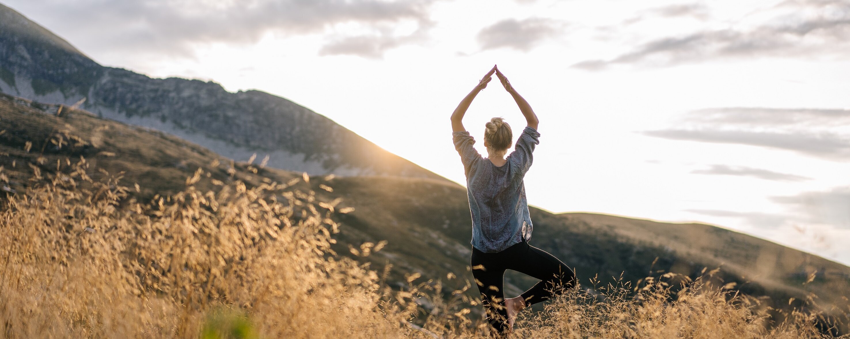 Junge Frau macht Yoga in den Bergen im Morgenlicht