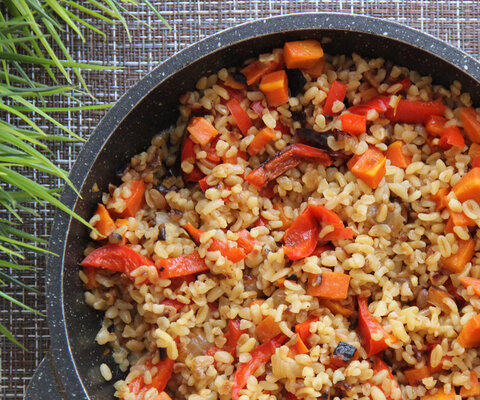  Eine Pfanne mit Bulgur und Paprikastücken. Daneben Schnittlauch.