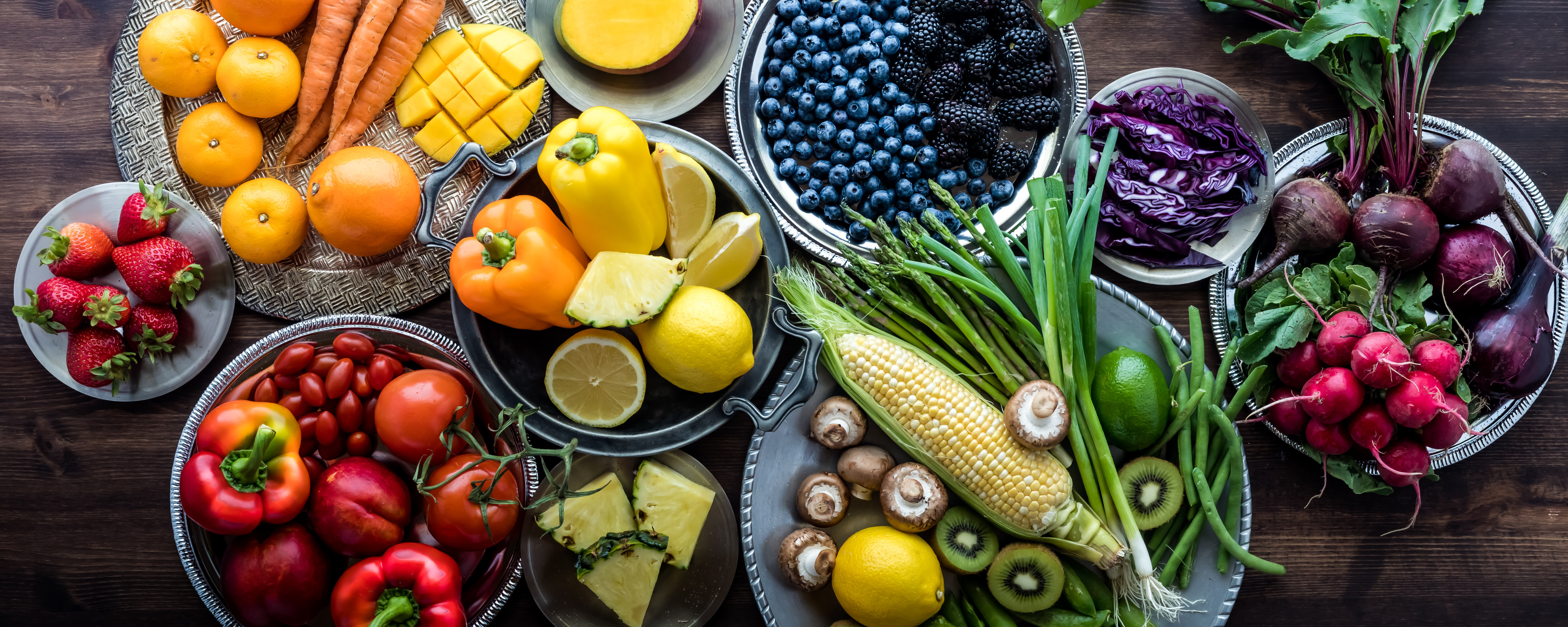 Obst und Gemüse in vielen verschiedenen Farben liegen auf diversen Tellern.