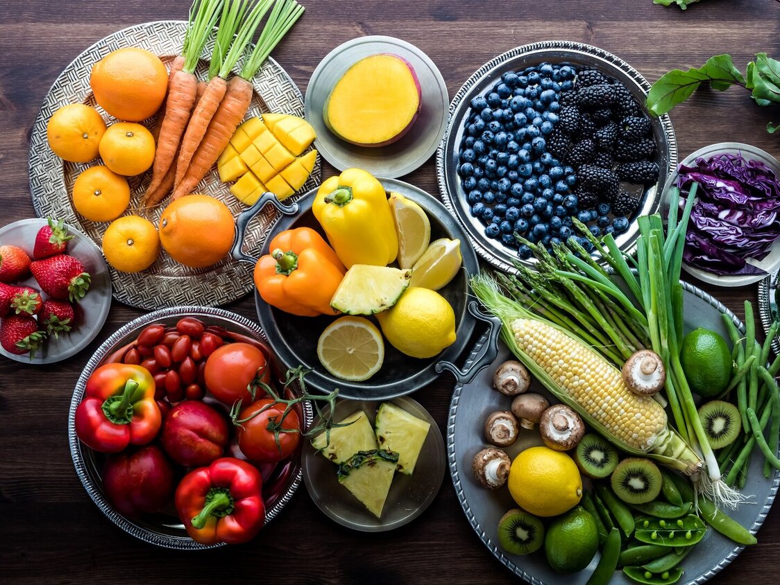 Obst und Gemüse in vielen verschiedenen Farben liegen auf diversen Tellern.