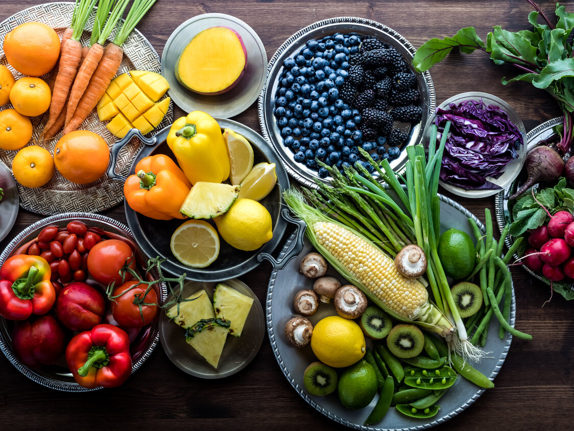 Obst und Gemüse in vielen verschiedenen Farben liegen auf diversen Tellern.