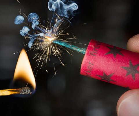 Feuerwerkskörper wird mit einem Streichholz angezündet.