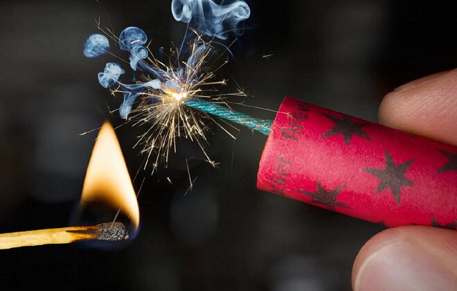 Feuerwerkskörper wird mit einem Streichholz angezündet.