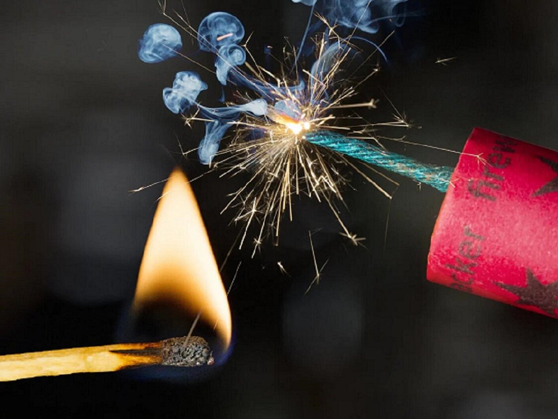 Feuerwerkskörper wird mit einem Streichholz angezündet.