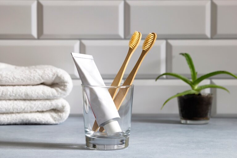 Zwei Zahnbürsten und eine Tube Zahnpasta in einem Glas