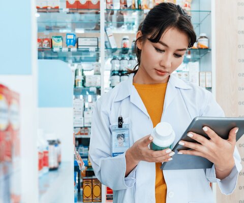 Eine Apothekerin schaut auf ein Tablet.
